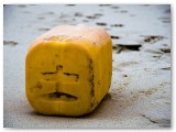Weathered yellow can washed up on a beach
