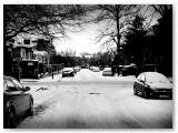 Snowy street with parked cars, in black and white