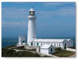 White lighthouse on a clifftop under a blue sky